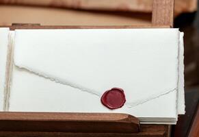 Stack of handmade paper invitations with red sealing wax in wooden box photo