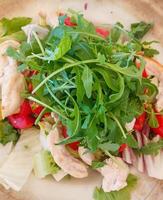 Fresh salad with arugula, chicken, tomatoes, and endive, resting on a plate photo