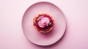 A top-down view of a delicate tart with vibrant pink mousse, garnished with thin radish slices, a small pink rose, and fresh sage leaves, presented on a soft pink plate. photo