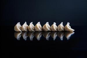 A row of meticulously crafted dumplings, glowing softly as if illuminated from within, positioned on a sleek, reflective black surface that captures their perfect reflections photo