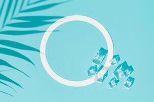 Summer day scene with ice cubes and tropical palm leaves shadow on blue background. An original background image with a play of light and shadow. Minimal concept. Flat lay, top view. Copy space. photo