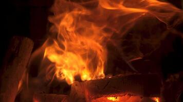 Flickering flames leap and sway in a rustic fireplace, casting a warm glow in the dimly lit room, creating an inviting atmosphere on a chilly evening. video