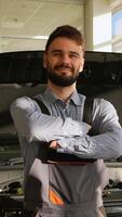 Smiling auto mechanic standing in front of open car hood video