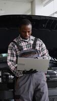 Auto mechanic using laptop for engine diagnostics in workshop video