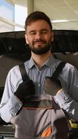 Smiling auto mechanic standing in front of open car hood video