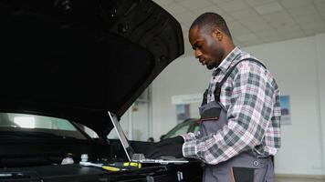 Auto mechanic using laptop for engine diagnostics in workshop video
