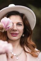 Woman holds magnolia flowers, surrounded by blossoming trees. Captured during spring, showcasing natural beauty and seasonal change. photo
