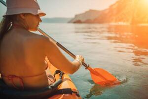 Woman in kayak back view. Happy woman with long hair in a swimsuit and hat floating in kayak on the sea. Summer holiday vacation. Summer holidays vacation at sea. photo
