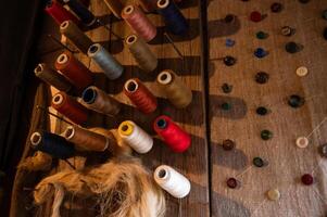 A variety of spools and thread on a wooden table photo
