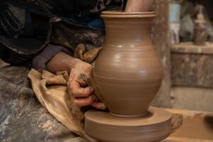 A person is making a pottery vase on a pottery wheel photo