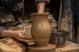 A potter is making a vase on a potter wheel photo