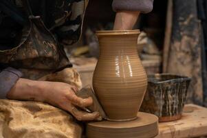 a person is making a vase on a potter's wheel photo