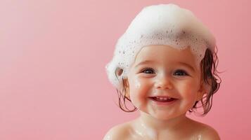 Joyful baby with bubbly bath foam on head, against soft pink backdrop, radiates pure happiness. A simple, sweet moment of babyhood. photo