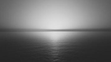 Serene monochrome ocean view with a radiant horizon line under a soft, cloud-filtered sky. photo