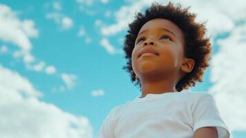 Young boy looking up at the blue sky filled with clouds, showcasing a sense of wonder, imagination and dreams of the future. photo