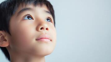 Boy looking up with curious eyes, reflecting wonder and innocence in bright light, his face expressing hope and dreams for the future. photo