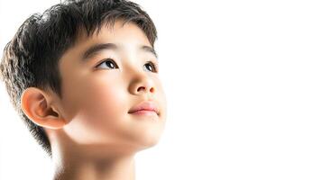Portrait of a young boy, looking up with hope and wonder, against a bright white backdrop, evoking feelings of curiosity and aspiration. photo
