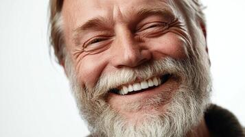 Close-up of a happy, mature man with a full, gray beard and a bright smile. He has wrinkles around his eyes, conveying joy and experience. photo