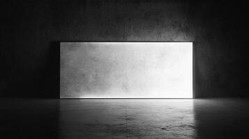 Illuminated rectangular panel on a dark concrete wall casting light across a bare floor creating contrast in a stark, minimalist setting. photo