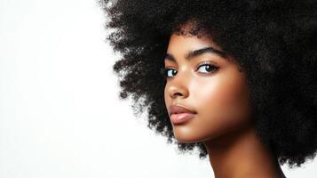 Portrait of a young woman with striking features, dark eyes, and natural hair. She is against a light background with copy space to her left. photo