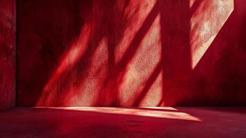 A red room with light shining on the wall creates a stark contrast of light and shadow that enhances the texture of the rough surface. photo