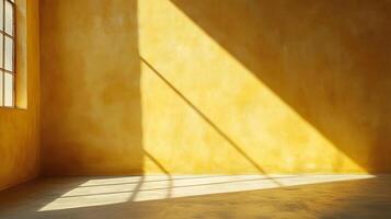 An empty room bathed in warm light, with sunshine streaming through a window and casting a striking diagonal shadow across a golden wall. photo