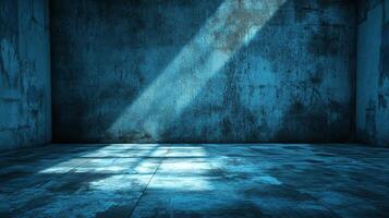 Light streams into a blue-toned concrete room, creating a stark contrast between illuminated patches and shadowy corners, evoking emptiness. photo