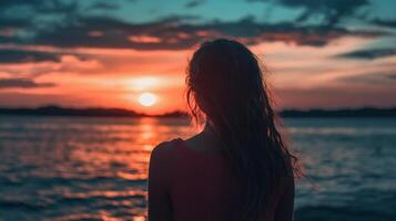A silhouette gazing at the setting sun's vibrant colors, casting a serene reflection on the water. Peaceful nature, serene beauty. photo