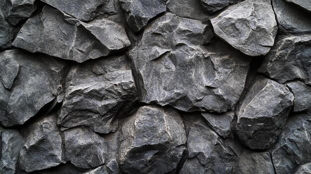 Close up view of a rocky dark gray wall made of stacked stones with sharp edges, creating a solid and textured background surface. photo