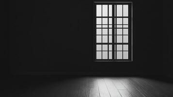 A dark, empty room is illuminated by the light filtering through a window with a black frame, creating a stark contrast on the wooden floor. photo