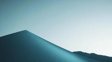 Minimalist landscape showing a sand dune gently sloping under a clear sky at sunrise, creating a serene and peaceful atmosphere photo