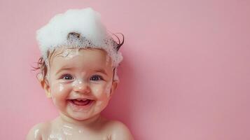A baby is covered in bubbles with a big smile. The background is pink and the baby is very joyful and clean after a fresh bath. photo