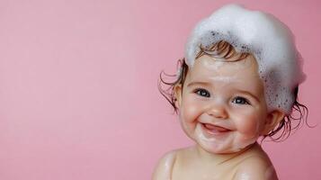Cute baby with bubbly soap suds on head, joyful face, and pink background. Innocence and bathing fun combine in this adorable image. photo