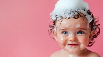 Adorable baby girl enjoying a bubbly bath. The baby is covered in soap bubbles, looking happy and clean on a pink background. photo