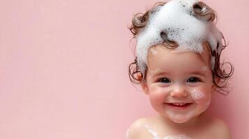 Smiling baby with a head full of shampoo bubbles against a solid pink background. Childcare and hygiene are key here. photo