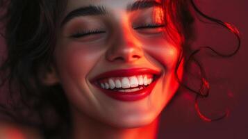 Radiant smile in red light. Close-up of a woman's face with a beaming smile, eyes closed, highlighted by vibrant red illumination. photo