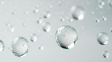 Macro image of transparent water droplets floating against a light gray background, showcasing their spherical shapes and refracted light. photo