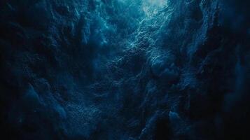 Abstract textured landscape with a dark, moody atmosphere. The deep blue tones create a sense of depth and mystery, and a light source above. photo