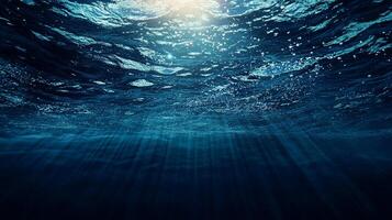 Underwater view with sunlight filtering through waves, creating a serene and mysterious blue ambiance. Deep ocean exploration. photo