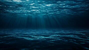 Underwater rays of light pierce the depths of the dark sea, creating an ethereal atmosphere under the rippling surface. photo