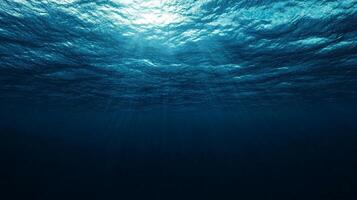 Underwater scene with sunlight piercing through the water's surface, creating a serene and mysterious atmosphere in the deep blue ocean. photo