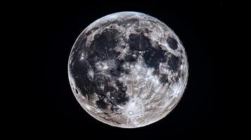 Detailed view of the moon with craters and textures. The moon is set against a black background, emphasizing its lunar surface. photo