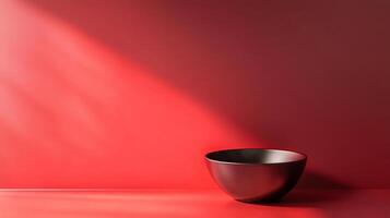 A striking, abstract portrayal of a black bowl positioned against a bold red backdrop inspires thoughts of simplicity and sophistication in a minimalist aesthetic. photo