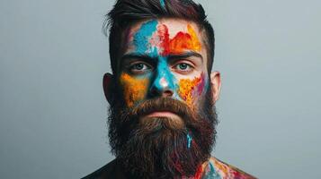 Man's face covered in a vibrant mix of colors, set against a plain background, shows emotion, expression and creativity. photo