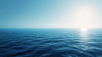Serene ocean view with gentle waves under a clear blue sky, the sun's reflection creating a calming and picturesque scene. photo