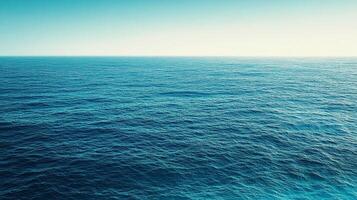 Vast expanse of the ocean meeting a clear horizon. Calm waters reflect the bright sky, showcasing a tranquil oceanic scene. photo
