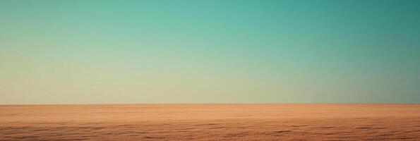Horizontal view of golden field under a clear turquoise sky, presenting a tranquil scene of nature's vastness and simple beauty. photo