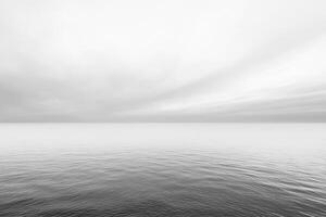 A serene monochrome landscape featuring a tranquil sea meeting a soft, cloud-filled sky, creating a peaceful and minimalist vista. photo