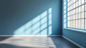 A room painted blue with a large window. The sun is streaming in, creating a beautiful light and shadow pattern on the wall and floor. photo