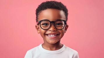 Smiling boy with eyeglasses poses in front of a pink backdrop. Happiness is radiating from his face in this close-up shot. photo
